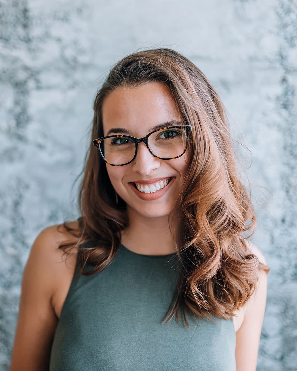 a woman wearing glasses and smiling at the camera